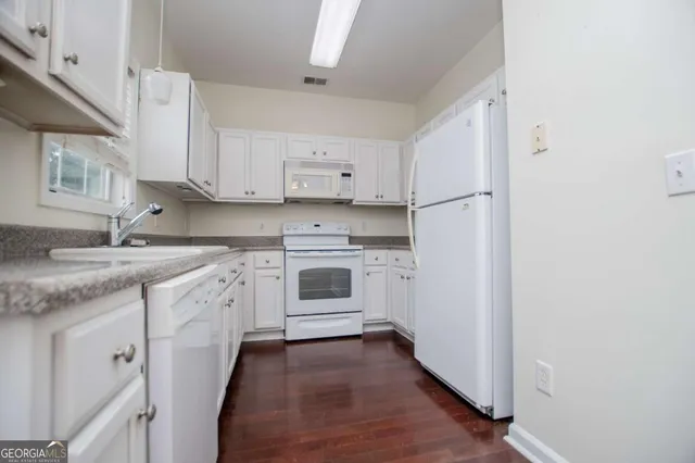 a kitchen with granite countertop white cabinets and white appliances