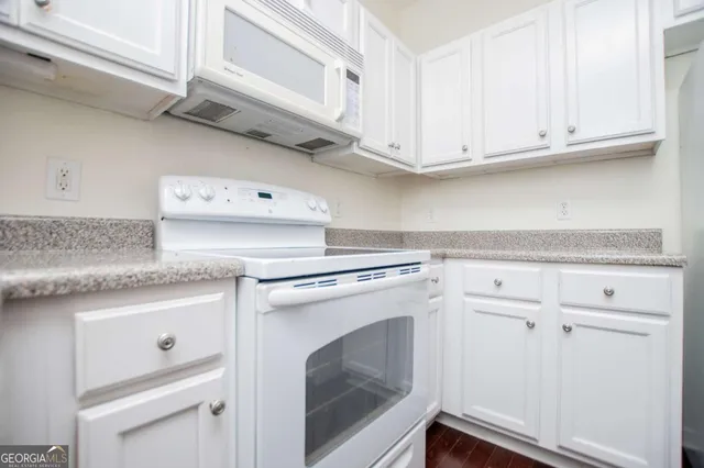 a kitchen with granite countertop white cabinets and white appliances