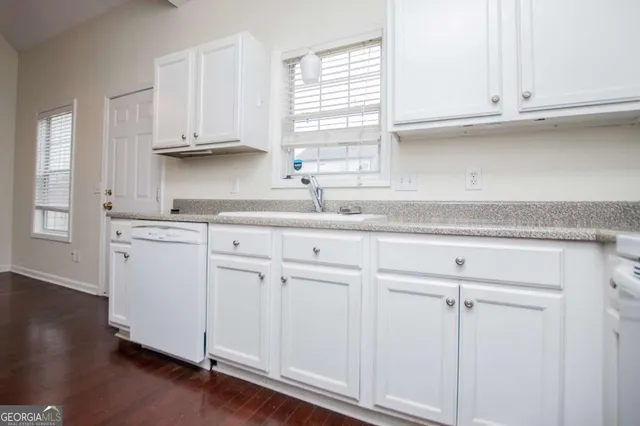 a kitchen with white cabinets and a window