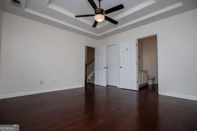 an empty room with wooden floor a ceiling fan and closet