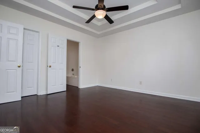 an empty room with wooden floor a ceiling fan and closet