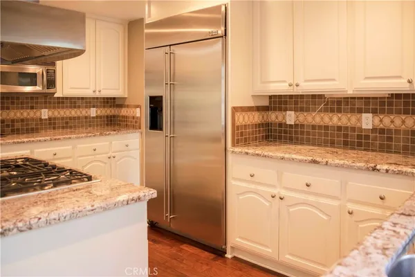 a kitchen with granite countertop white cabinets and stainless steel appliances
