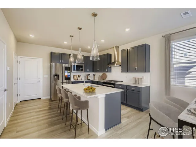 a kitchen with stainless steel appliances kitchen island granite countertop a sink and a refrigerator