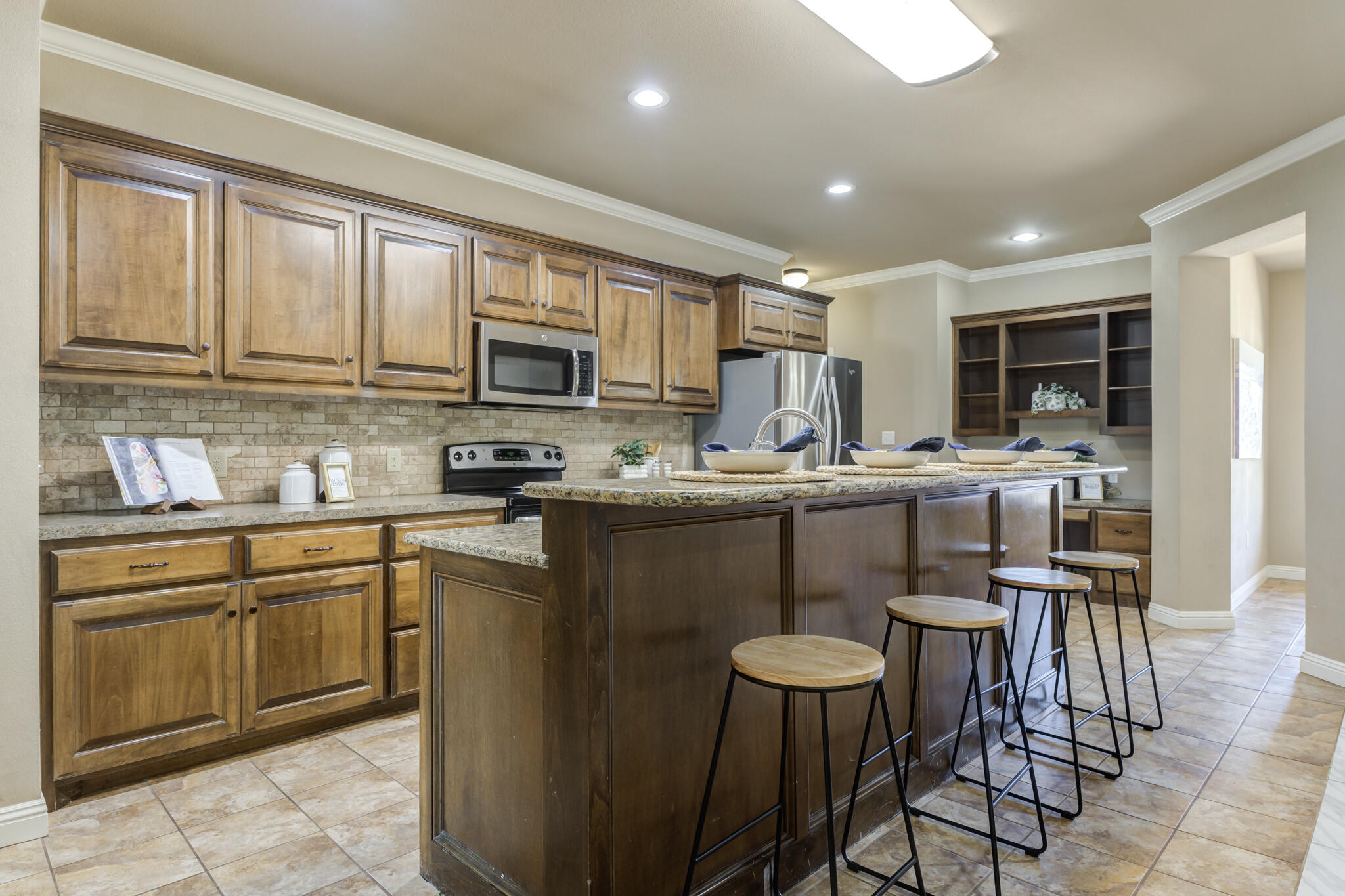 6512 71st Street Lubbock, TX 79424 - Photo 12 of 41 a kitchen with stainless steel appliances granite countertop a stove a sink a microwave a dining table and chairs