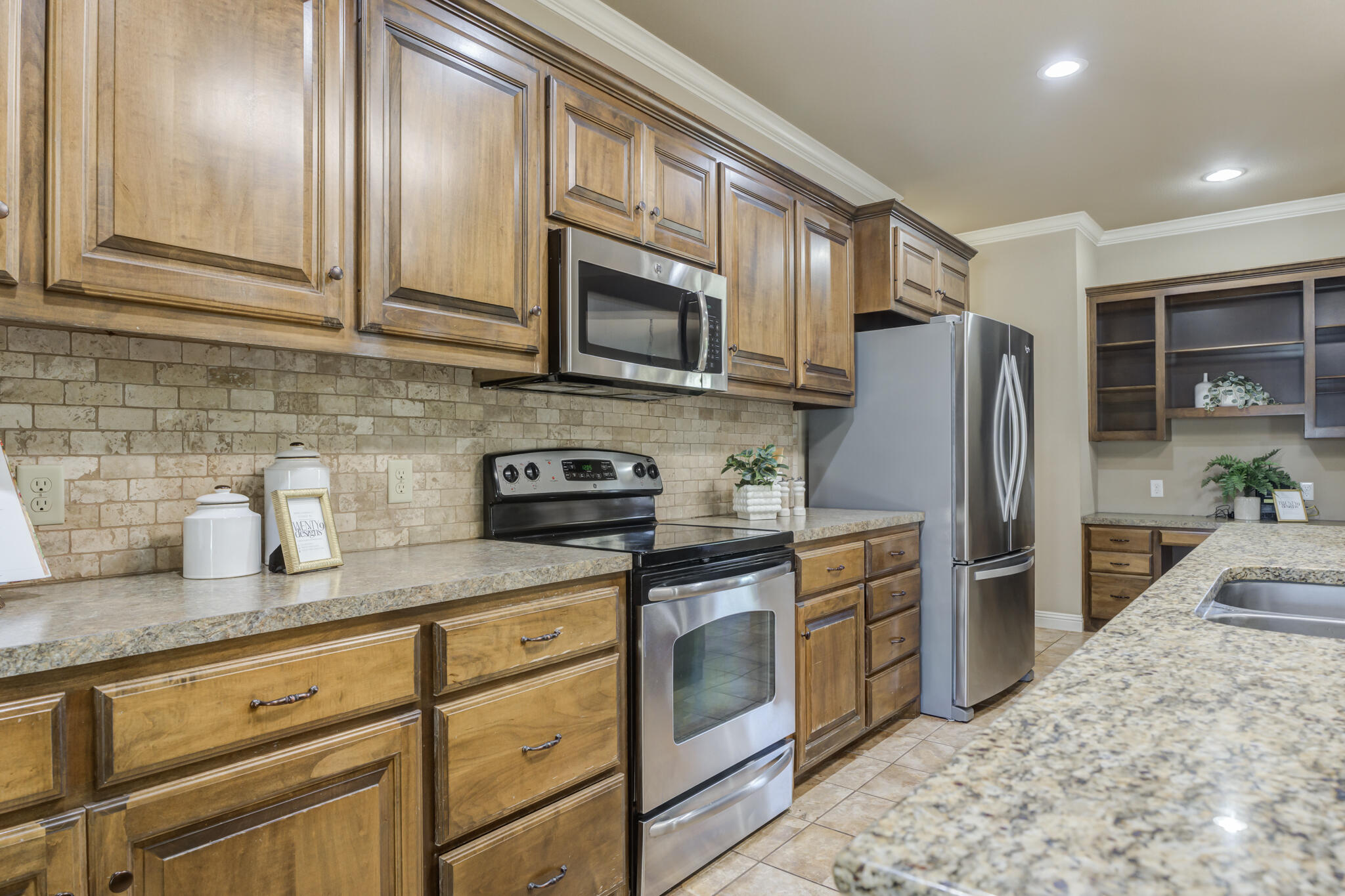 6512 71st Street Lubbock, TX 79424 - Photo 13 of 41 a kitchen with stainless steel appliances granite countertop a refrigerator a stove top oven a sink and dishwasher