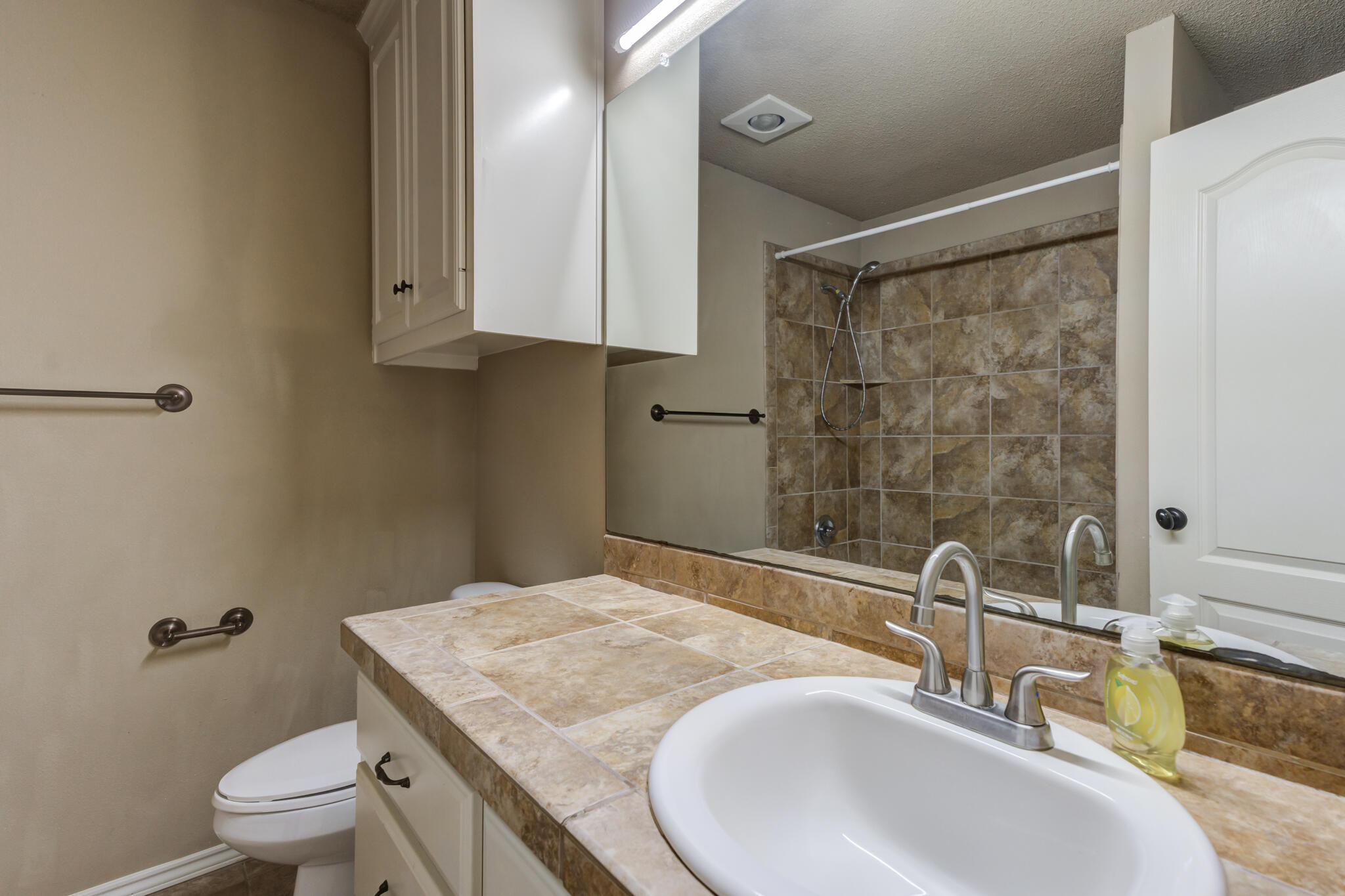 6512 71st Street Lubbock, TX 79424 - Photo 31 of 41 a bathroom with a granite countertop sink a toilet and a mirror
