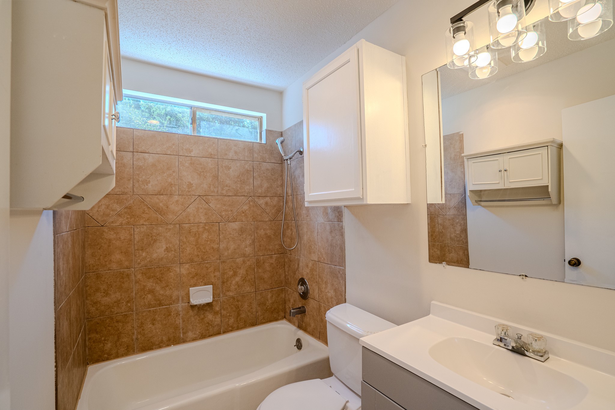 517 Cutty Trail, Unit B Lakeway, TX 78734 - Photo 13 of 16 A well-appointed bathroom with tile shower surround and a clean vanity with mirror and storage.