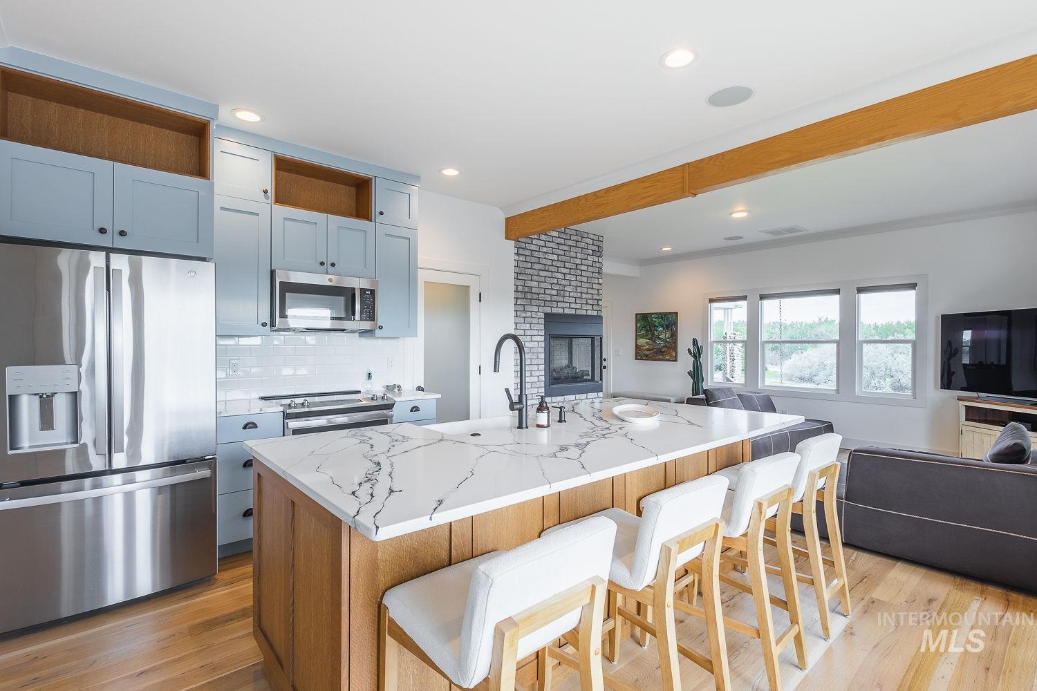 11171 Pump Road Nampa, ID 83686 - Photo 13 of 50 Gourmet kitchen with light blue cabinetry, stainless steel appliances, and a large central island featuring a white quartz countertop
