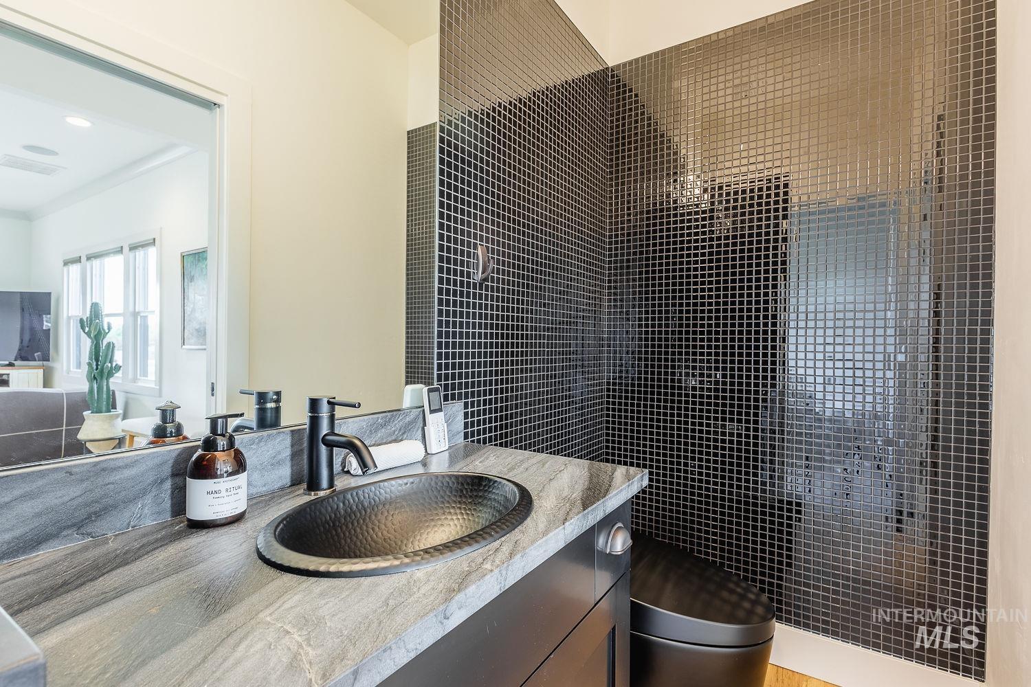 11171 Pump Road Nampa, ID 83686 - Photo 25 of 50 Bathroom featuring a black hammered vessel sink with a matte black faucet, set into a gray variegated countertop