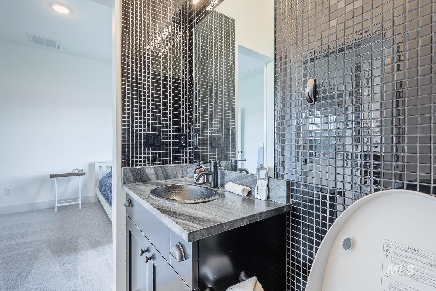 11171 Pump Road Nampa, ID 83686 - Photo 26 of 50 Vanity with a hammered metal vessel sink, stone countertop, and dark wood cabinetry