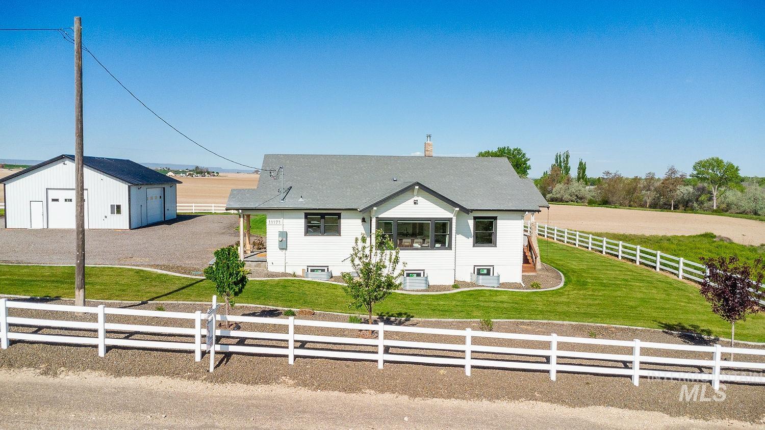 11171 Pump Road Nampa, ID 83686 - Photo 44 of 50 White ranch-style residence featuring a gray shingle roof, dark-framed windows, and a foundation with visible basement window wells