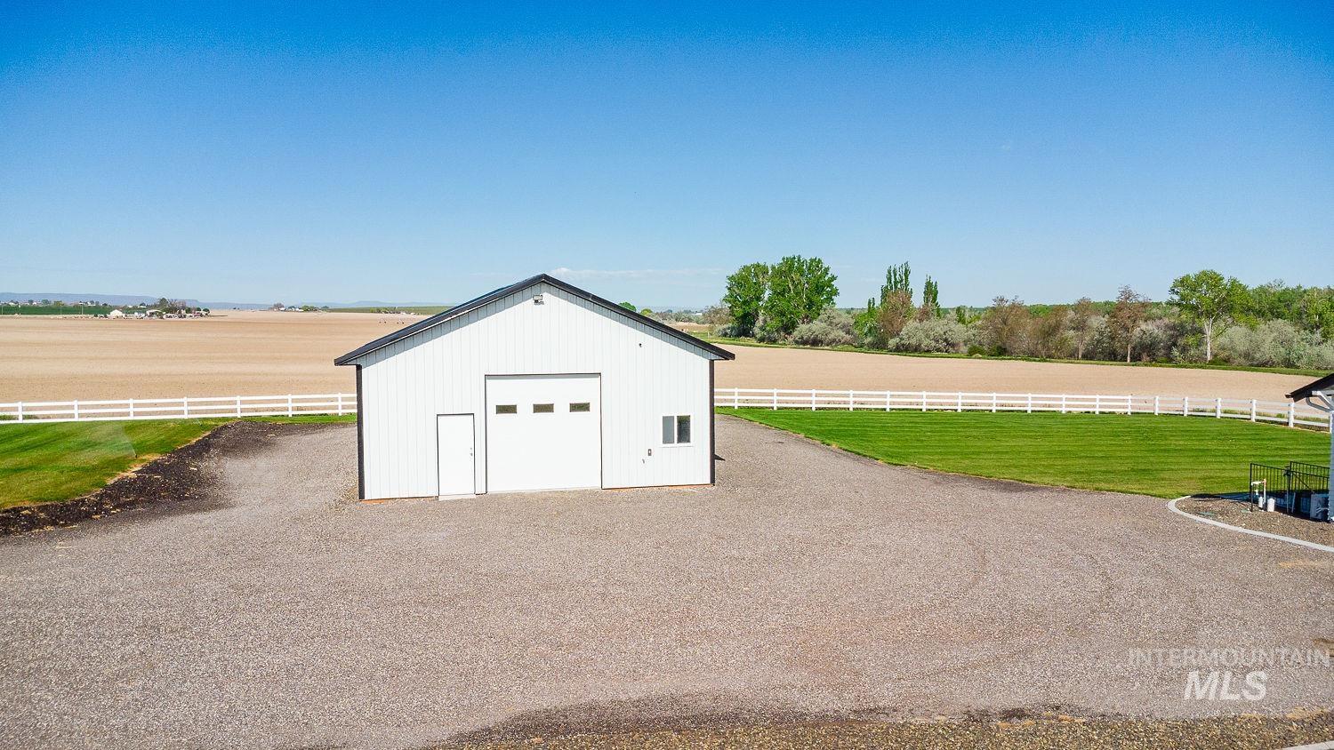 11171 Pump Road Nampa, ID 83686 - Photo 45 of 50 White pole barn with a black gable roof and roll-up garage door, featuring an additional entry door and window