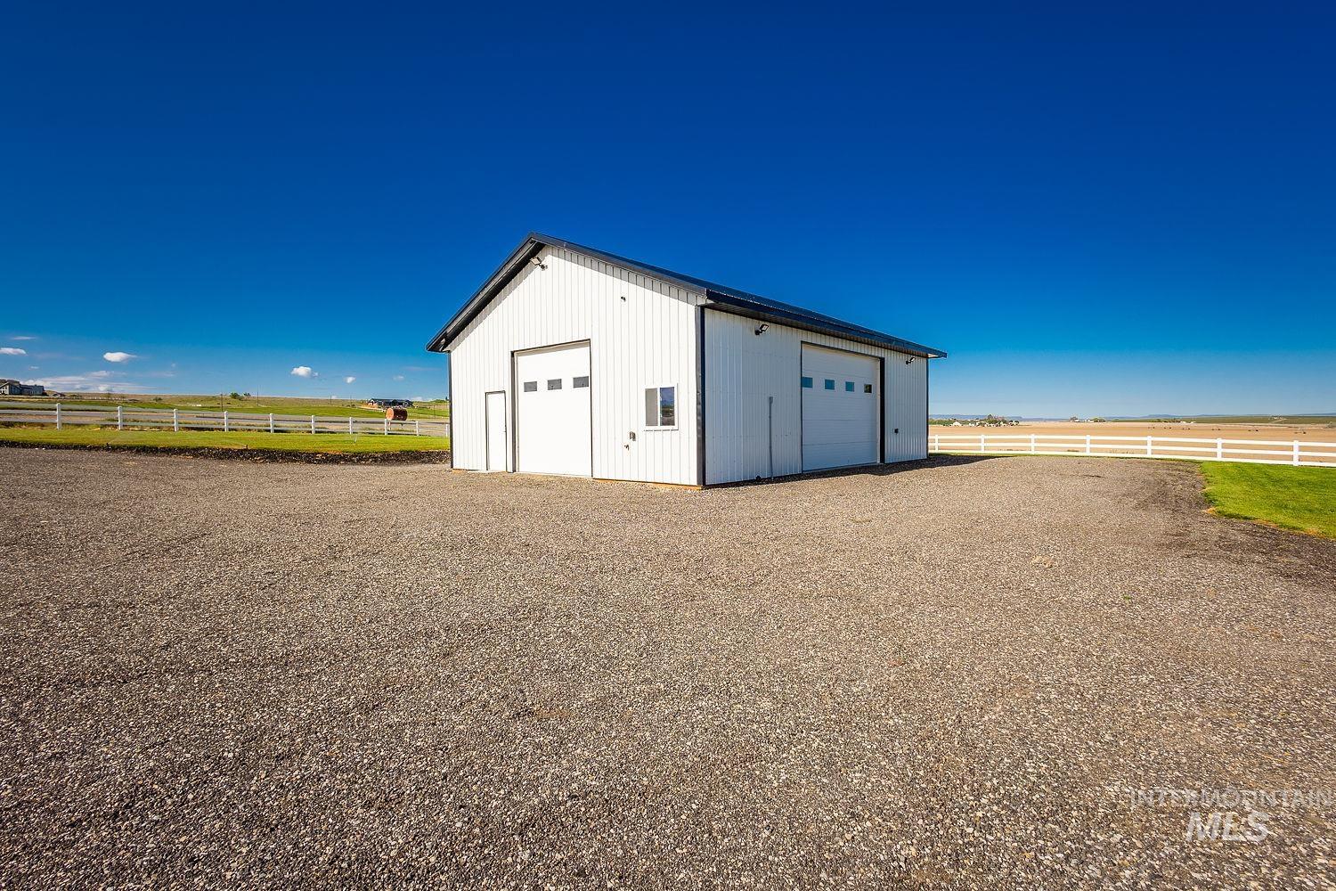 11171 Pump Road Nampa, ID 83686 - Photo 46 of 50 White metal-sided outbuilding featuring two large garage doors, a single entry door, and a black shingle roof