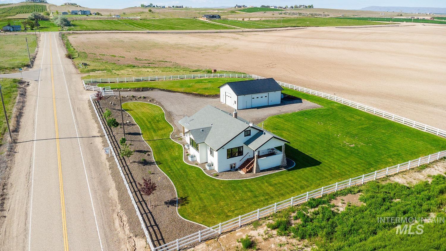 11171 Pump Road Nampa, ID 83686 - Photo 48 of 50 Expansive property featuring a white residence with a dark roof, a detached two-car garage, and surrounding green lawns