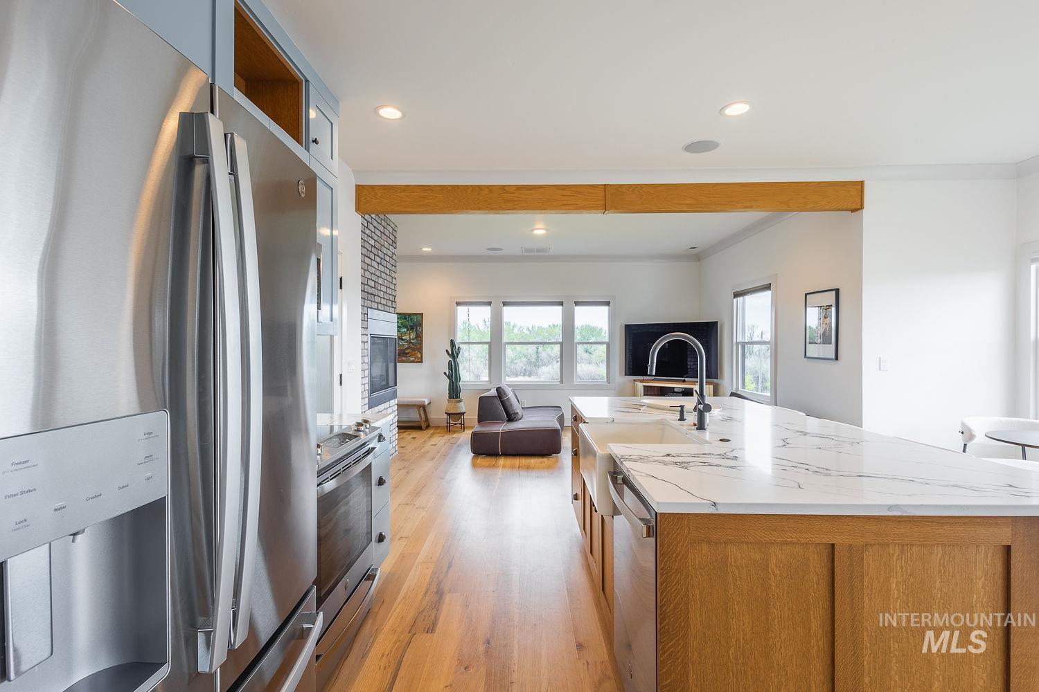 11171 Pump Road Nampa, ID 83686 - Photo 8 of 50 Stainless steel side-by-side refrigerator, wood-finish flooring, and a kitchen island with stone countertops and an integrated farmhouse sink
