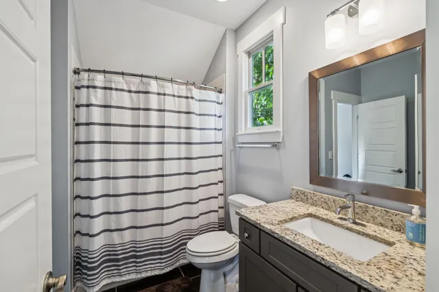 a bathroom with a sink a toilet a mirror and shower curtain