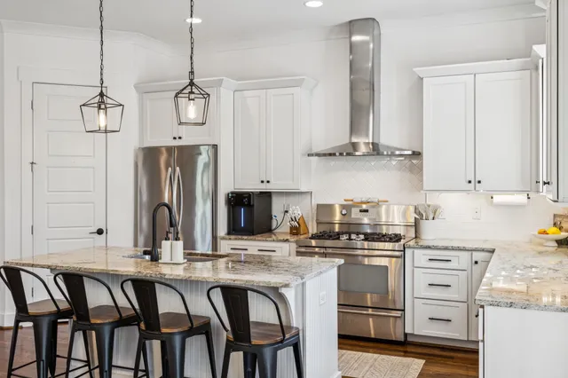 a kitchen with stainless steel appliances granite countertop a stove a sink and a refrigerator with wooden floor