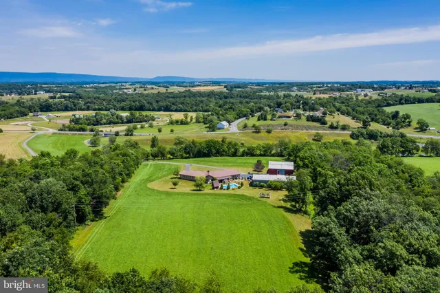 an aerial view of a house with swimming pool and trees