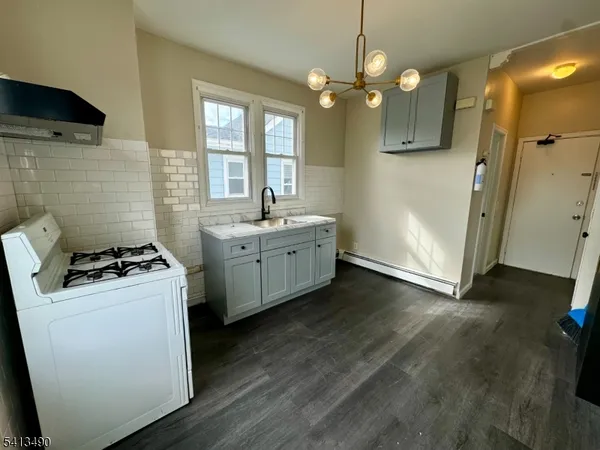 a kitchen with stainless steel appliances a sink a stove a refrigerator cabinets and wooden floor