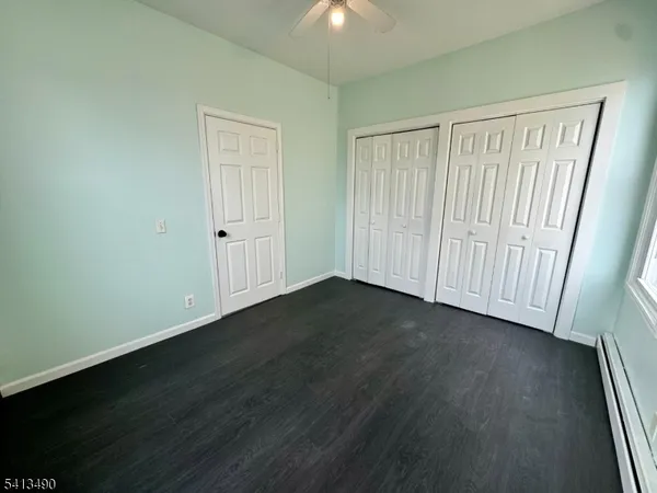an empty room with wooden floor and windows with curtains