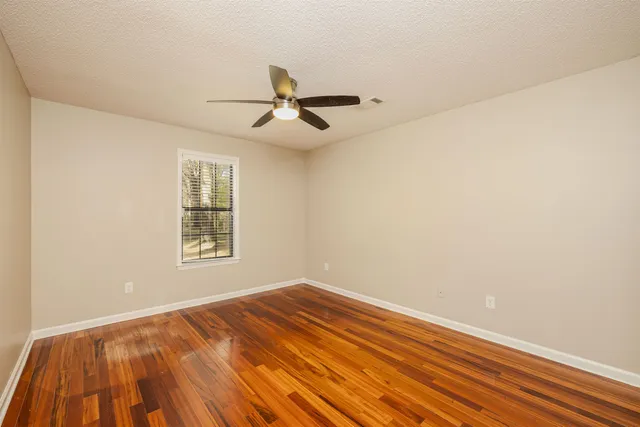 a view of empty room with wooden floor and fan