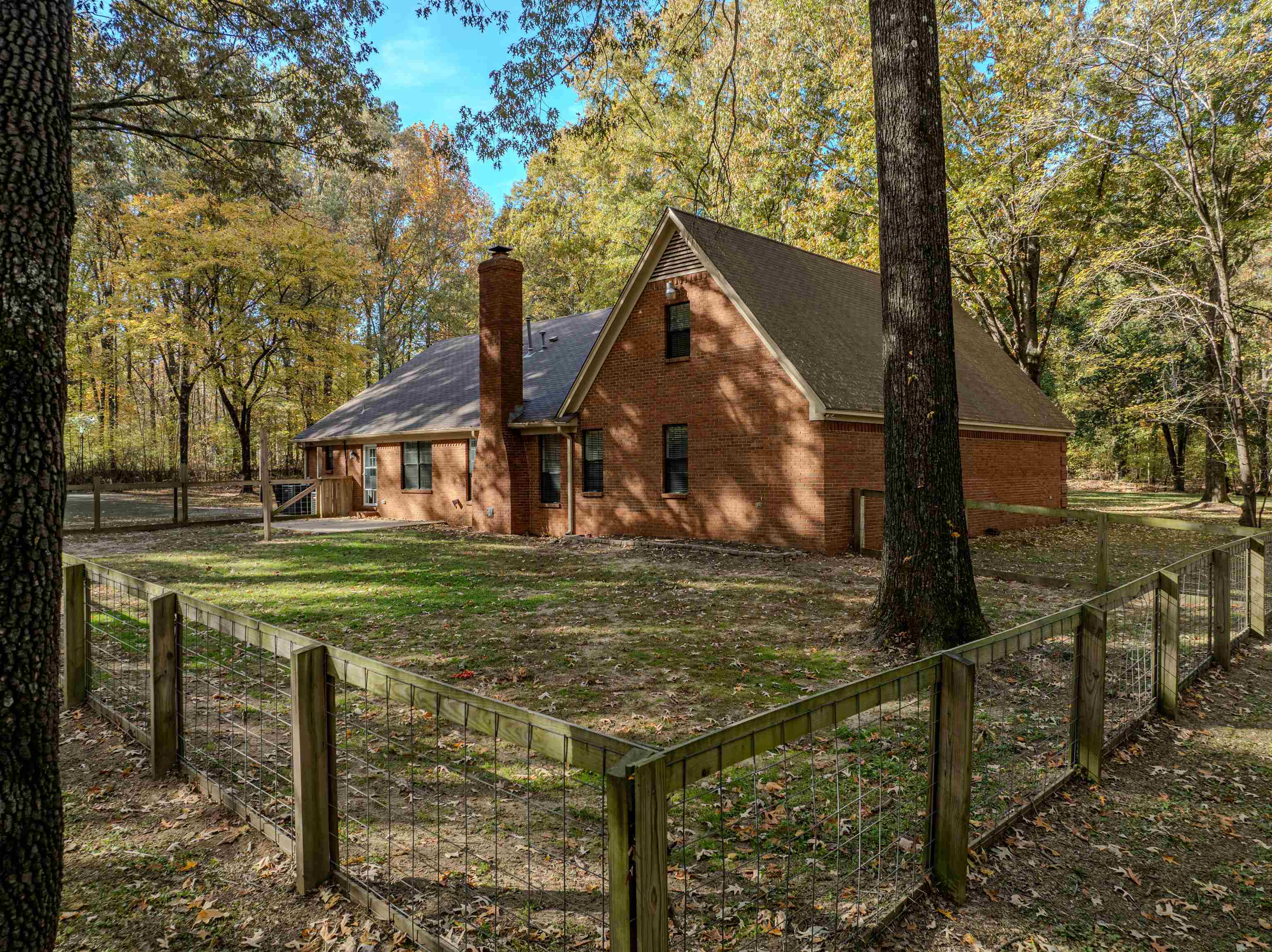 4808 Oak Road Bartlett, TN 38002 - Photo 26 of 35 View of back facade with a fenced backyard, brick siding, a chimney, a shingled roof, and view of wooded area
