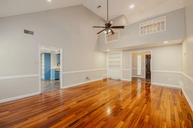a view of empty room with wooden floor and fan