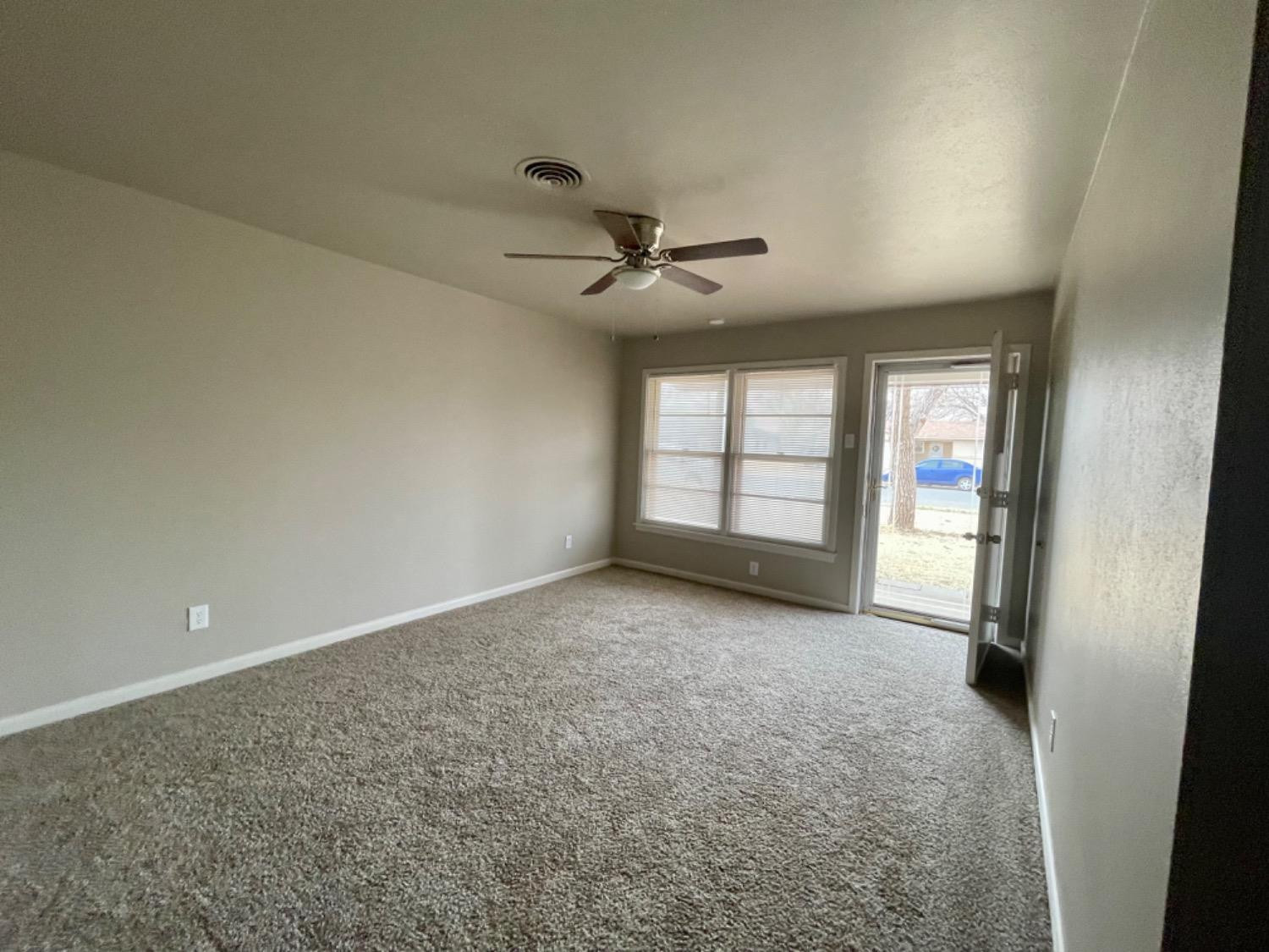 1201 Adrian Street Lubbock, TX 79403 - Photo 3 of 19 an empty room with windows and ceiling fan