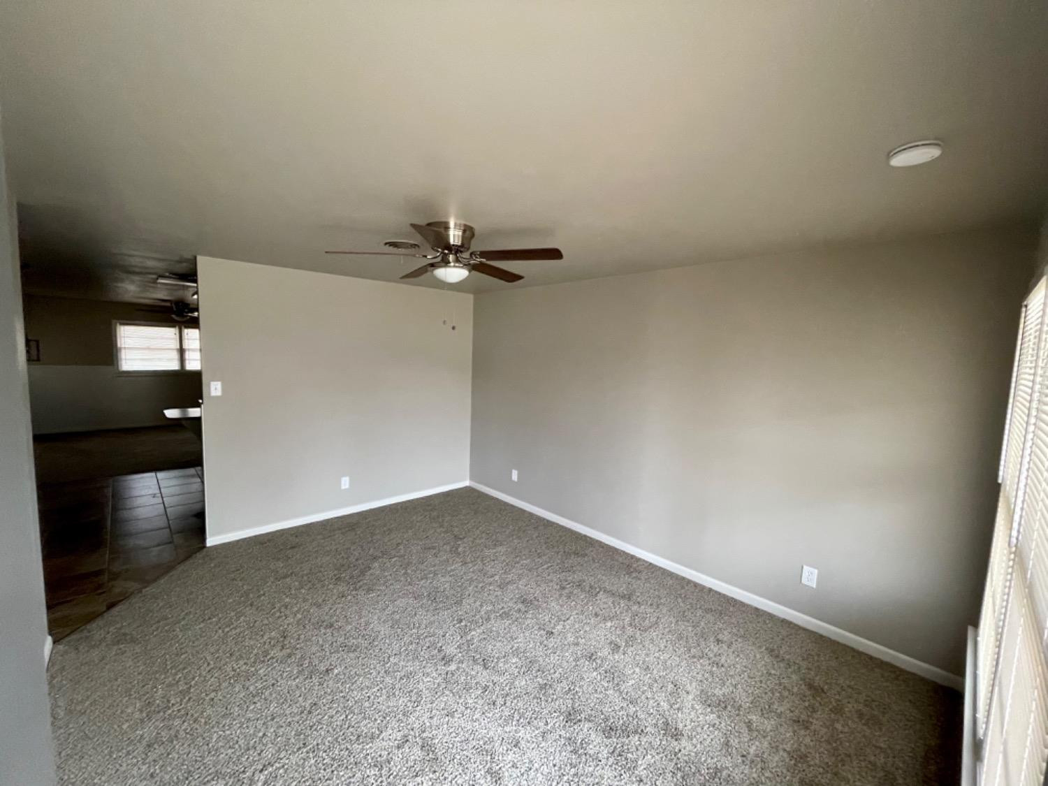 1201 Adrian Street Lubbock, TX 79403 - Photo 4 of 19 an empty room with kitchen view and wooden floor