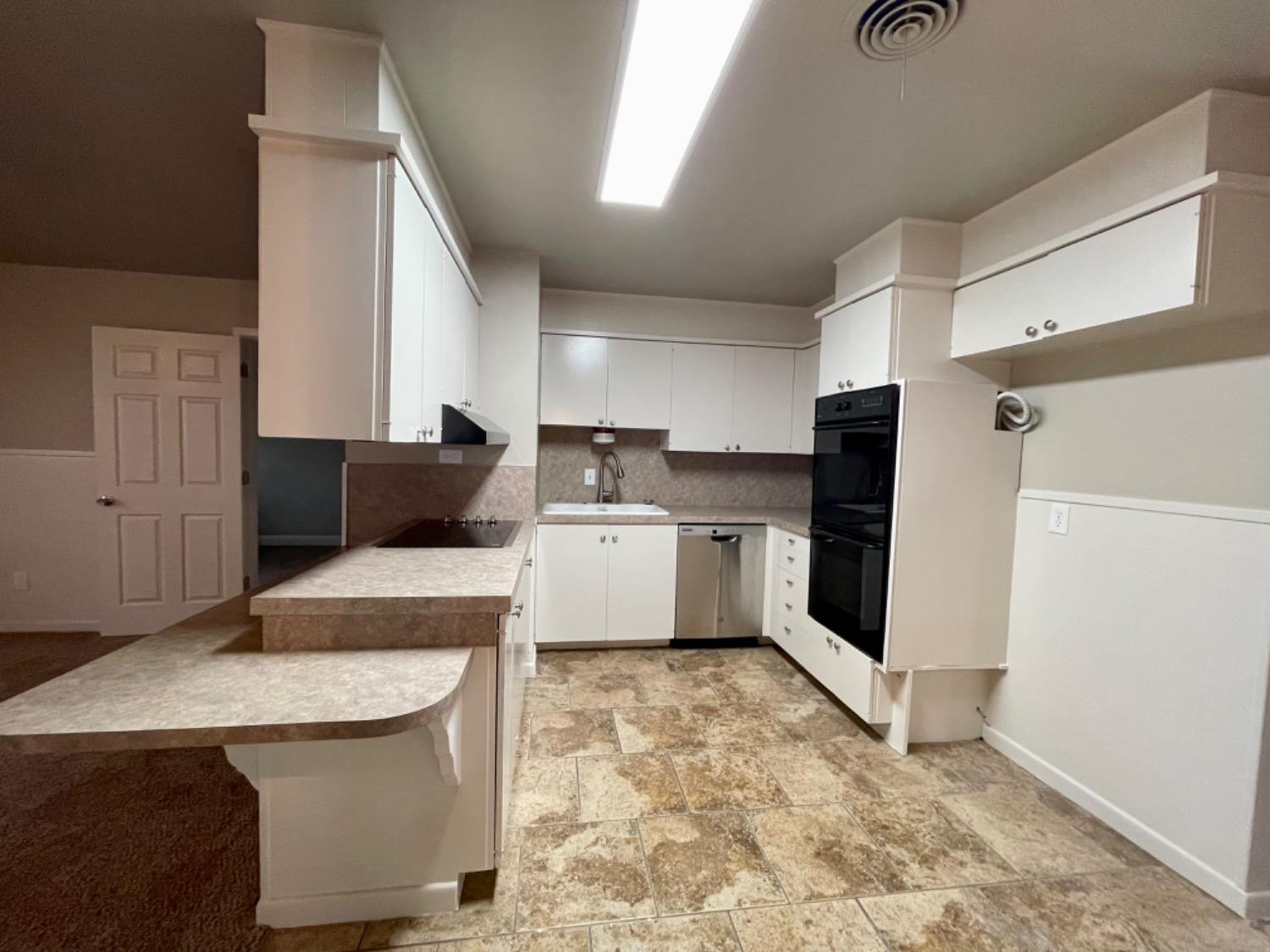 1201 Adrian Street Lubbock, TX 79403 - Photo 7 of 19 a kitchen with stainless steel appliances kitchen island granite countertop a refrigerator a sink a stove a microwave and island