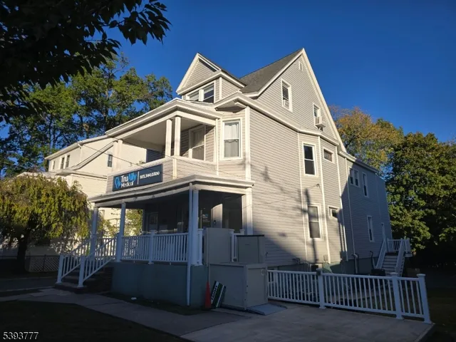 a view of a white house with large windows and a small yard