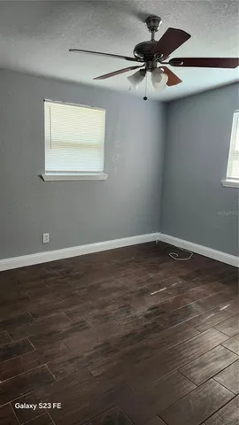 a view of a room with wooden floor a ceiling fan and windows