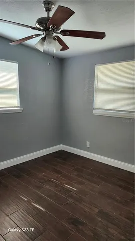 a view of an empty room with wooden floor and a window