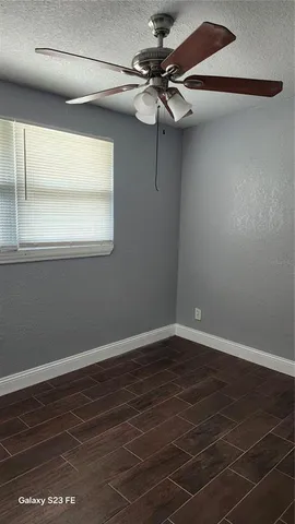 a view of a room with wooden floor fan and windows