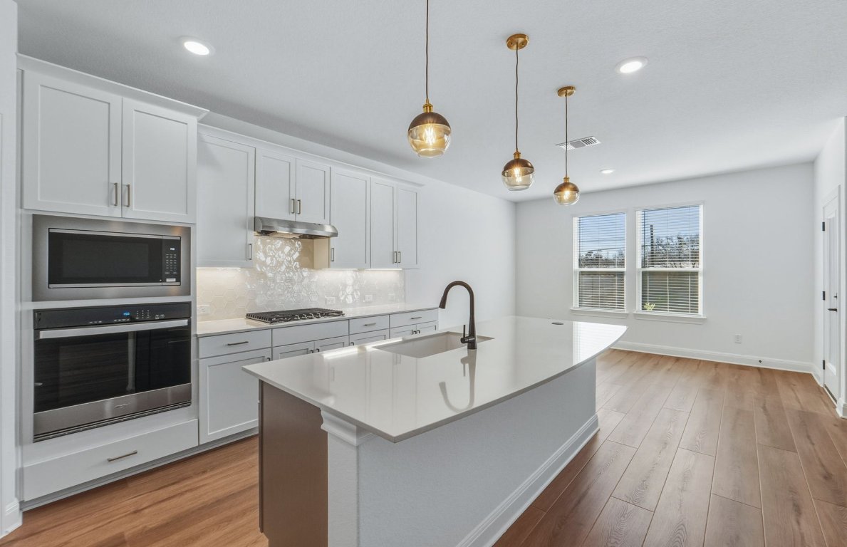 213 Regatta Trail Leander, TX 78641 - Photo 7 of 26 a kitchen with a sink a oven a counter space and a window