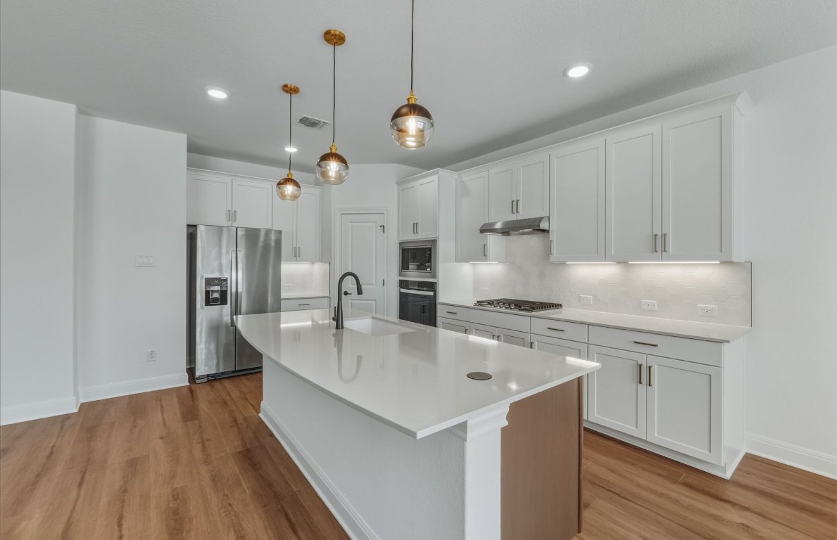 213 Regatta Trail Leander, TX 78641 - Photo 8 of 26 a kitchen with stainless steel appliances granite countertop a sink a stove and a refrigerator
