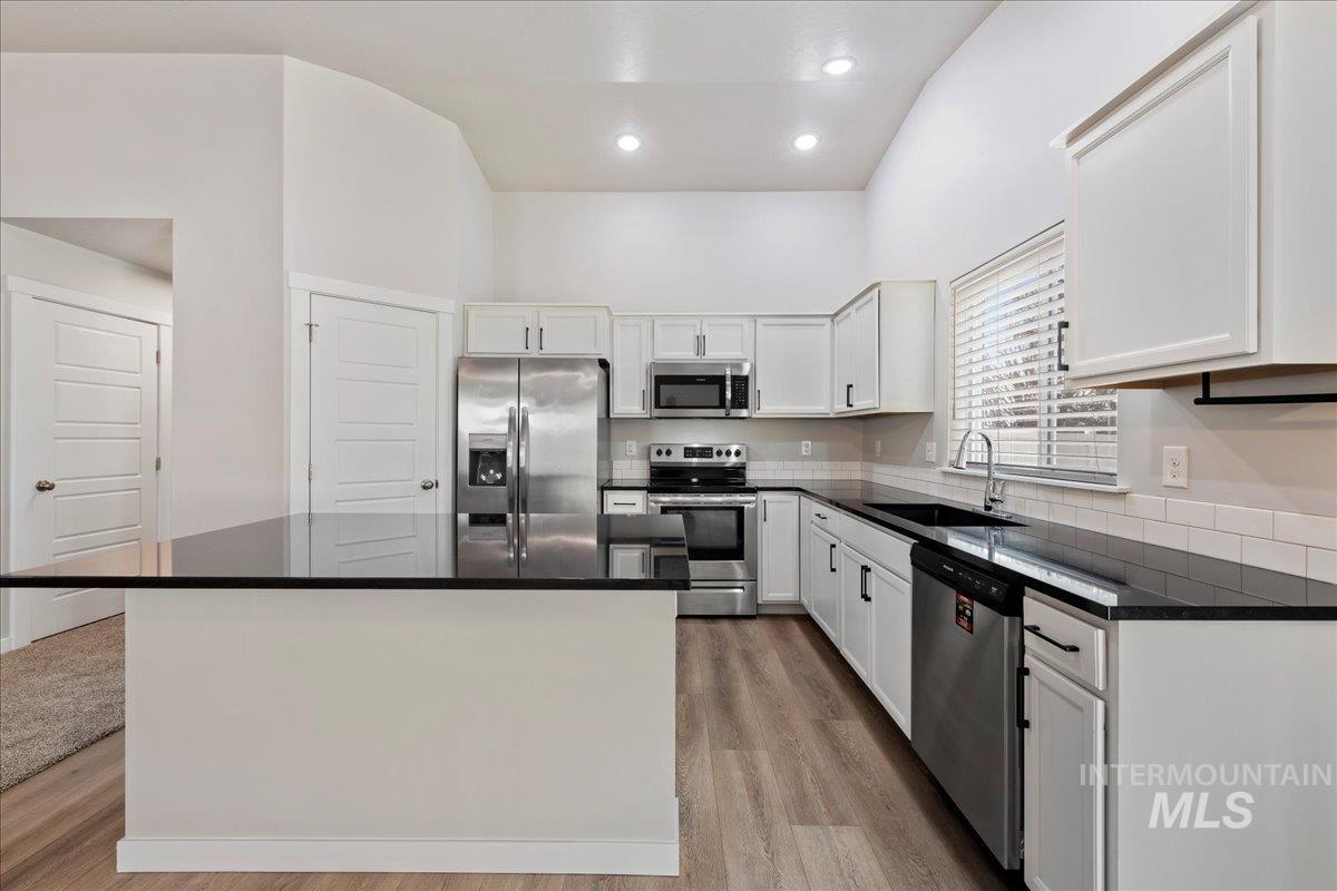 3085 S Green Boise, ID 83709 - Photo 12 of 32 Kitchen with stainless steel appliances, white cabinetry, light wood-style floors, recessed lighting, and a high ceiling