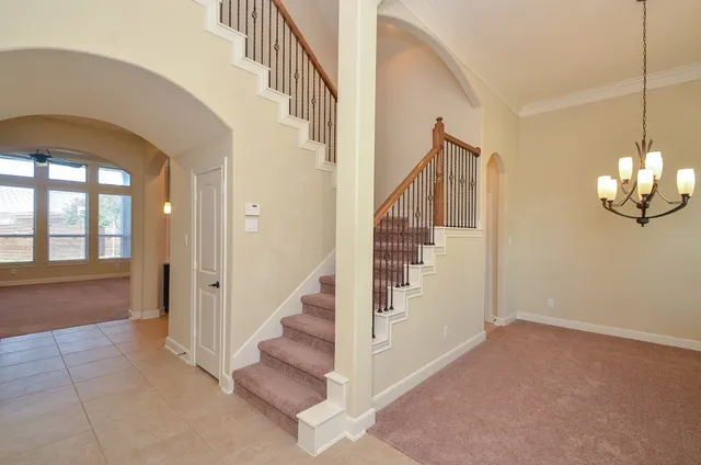 a view of staircase with large window and chandelier