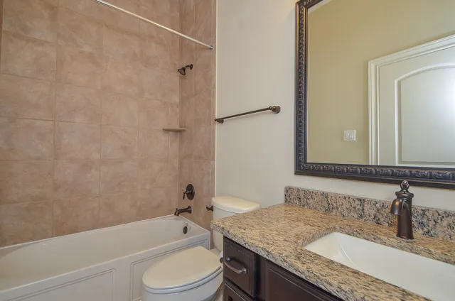 a bathroom with a granite countertop tub sink toilet and mirror