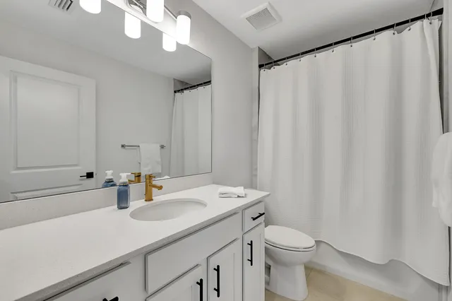 a bathroom with a sink a toilet and shower curtain