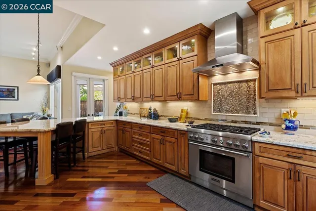 a kitchen with stainless steel appliances granite countertop a stove a sink dishwasher and cabinets with wooden floor