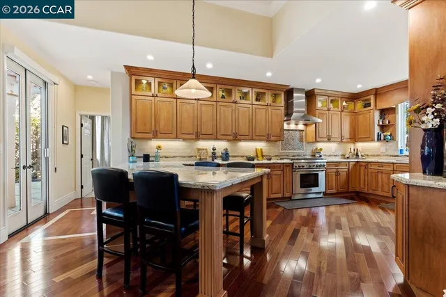 a kitchen with stainless steel appliances granite countertop a stove top oven a sink a dining table and chairs with wooden floor