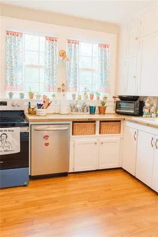 a kitchen with stainless steel appliances a stove a sink and white cabinets with wooden floor