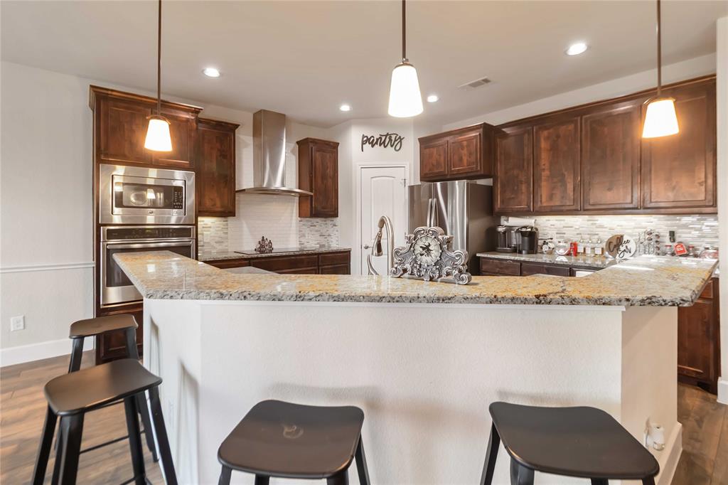 1663 Fraser Drive Burleson, TX 76028 - Photo 15 of 22 Kitchen with dark wood-type flooring, hanging light fixtures, light stone counters, backsplash, and recessed lighting