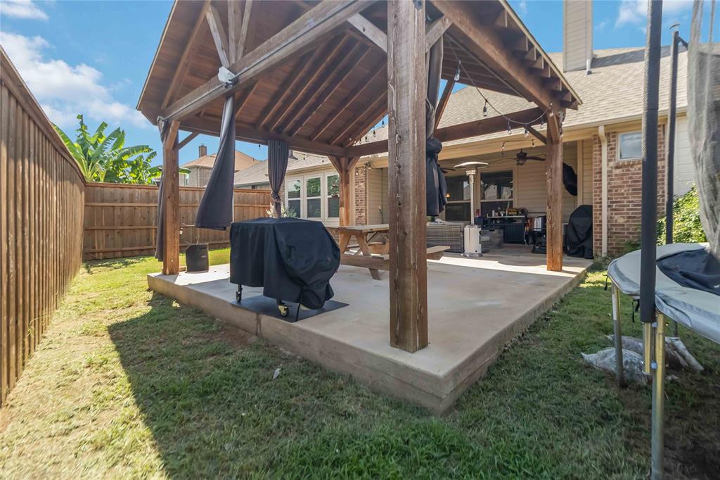 1663 Fraser Drive Burleson, TX 76028 - Photo 19 of 22 Fenced backyard featuring a patio area, a ceiling fan, a grill, and a trampoline