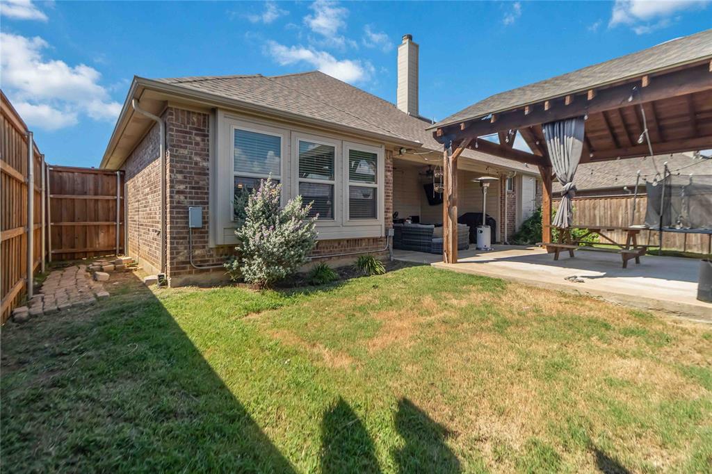 1663 Fraser Drive Burleson, TX 76028 - Photo 21 of 22 Rear view of property with a fenced backyard, a trampoline, brick siding, a patio, and a chimney