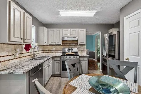 a kitchen with stainless steel appliances granite countertop a sink stove and refrigerator