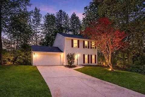 front view of house with a yard and a trees