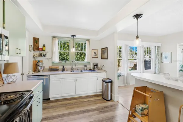 a kitchen with stainless steel appliances granite countertop a stove top oven a sink dishwasher a dining table and chairs with wooden floor