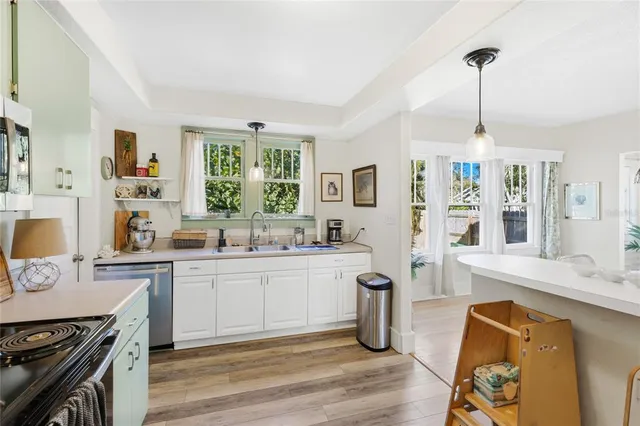 a kitchen with stainless steel appliances granite countertop a stove top oven a sink dishwasher a dining table and chairs with wooden floor